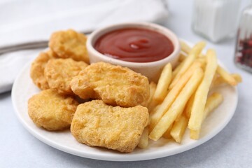Tasty chicken nuggets and french fries with sauce on light table, closeup