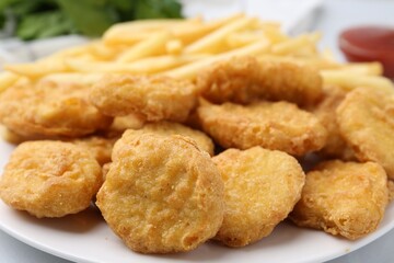 Tasty chicken nuggets and french fries on white table, closeup