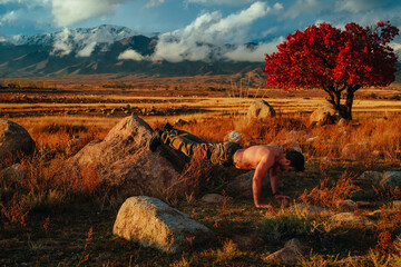 Young strong man doing push-ups on wild nature autumn background