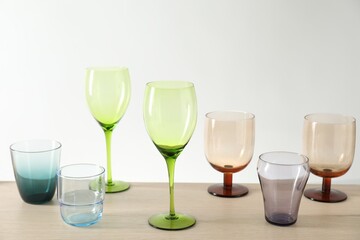 Many different glasses on wooden table against light background