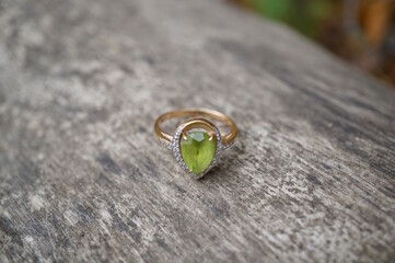 A precious ring with chrysolite on a wooden background.