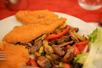 Breaded chicken fillets with beef stew and vegetables