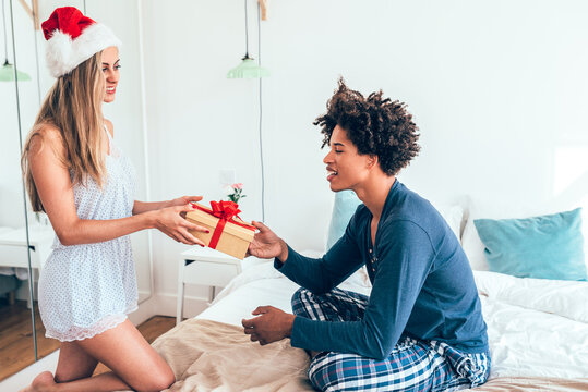 Christmas morning gift exchange between couple in cozy bedroom