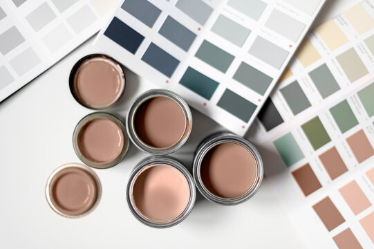 Tiny sample paint cans during house renovation, process of choosing paint for the walls, Mocha Mousse color of the year 2025, color charts on background