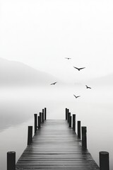 Serene dock extending into foggy water, birds soaring above in t