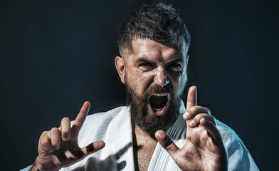 Karate man. Closeup portrait of professional karate instructor in white kimono. Strong bearded...