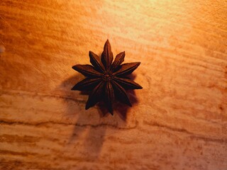 star anise with shadow on wood under warm yellow light
