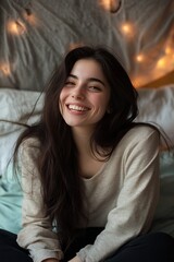 Obraz premium A woman with long hair is smiling and sitting on a bed
