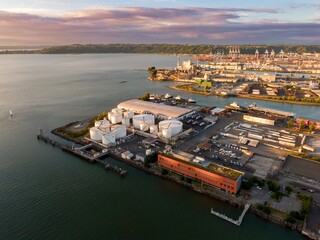 Aerial view of a bustling industrial port in Tacoma. Large storage tanks, docks, and cargo ships...