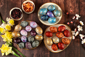 Easter celebration concept, Easter marble eggs colored with natural hibiscus tea, onion peel and curcumin, with sakura branch on wooden background. holiday card and ideas 