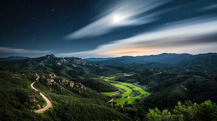   A picturesque valley with a meandering road upfront and majestic mountains behind
