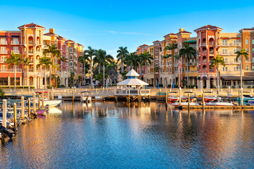 Obraz premium Morning light on Naples with waterfront buildings and boats under a clear sky.