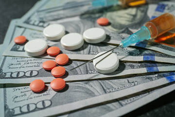 Drug addiction. Dollar banknotes, pills and syringe on gray table, closeup