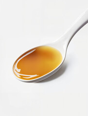 Spoon filled with golden syrup on a white background showcasing its smooth texture and rich color