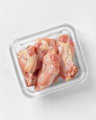 Fresh chicken drumsticks in a clear plastic container ready for cooking at a grocery store