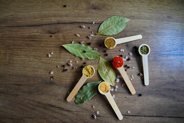 Mixture of different types of spices in wooden spoons on a wooden background 