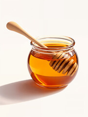 Golden honey in a glass jar with a wooden dipper resting inside on a light background