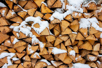 an outdoor woodpile covered with snow,  logs for ignition, background
