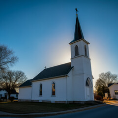 Fototapeta premium Beautiful white church with a tall steeple illuminated by golden sunset light, creating a peaceful and serene rural landscape