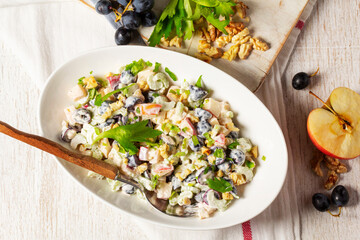 Waldorf salad with apples, celery, grapes and walnuts, dressed with mayonnaise and sprinkled with parsley.