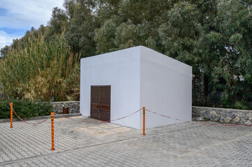 Minimalist white structure stands amid lush greenery in a tranquil outdoor setting