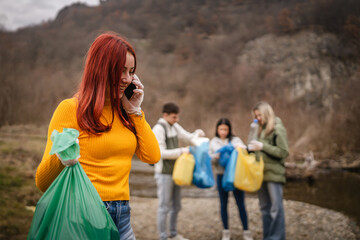 female teenager activist volunteer hold garbage and talk on cellphone