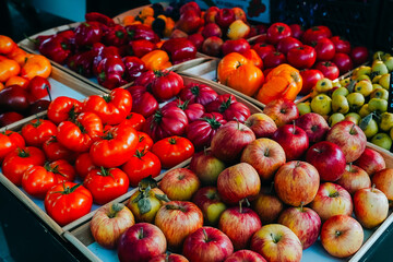 A colorful display of organic apples, tomatoes, and peppers at a farmer's market, highlighting fresh, seasonal, and gourmet produce in wooden crates.