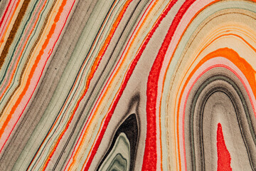close up of handmade marbled paper with pink, orange, green, gray, black lines
