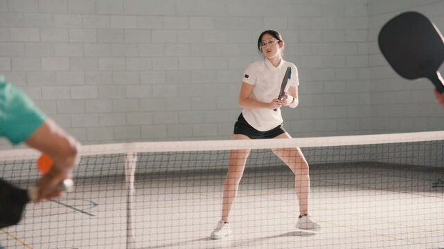 Adult pickleball players having a rally in a community gym