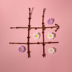 Tic tac toe with Easter elements white and purple flowers. Flat lay.