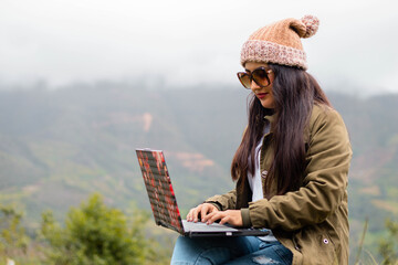 Mujer joven atractiva trabajando en laptop al aire libre durante sus vacaciones en la naturaleza.estilo de vida turista.