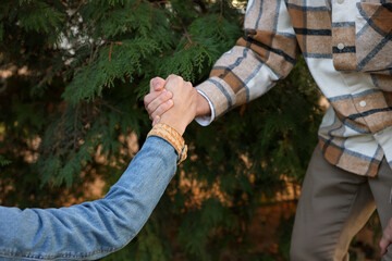 Help and support. People holding hands outdoors, closeup