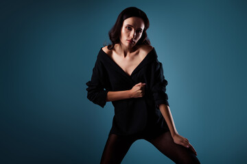 Elegant young woman in black jacket posing with confidence against a stunning blue gradient background