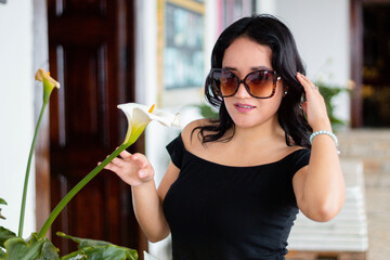 Retrato de mujer joven bonita con gafas belleza acariciando una flor blanca, elegancia y cuidado...