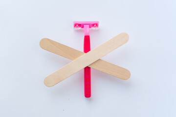 A pink razor crossed out with wooden spatulas – a symbol of rejecting shaving in favor of wax depilation. The idea of smooth skin without irritation and ingrown hairs.