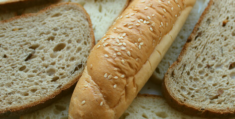 Bakery products are laid out after baking. Long hot dog buns and sliced ​​dark and light sandwich breads