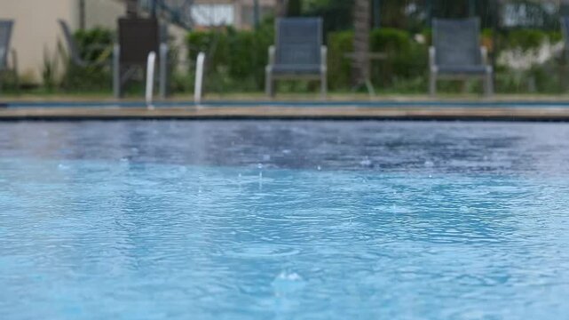 Closeup of pool water showing rain falling on a cloudy day.