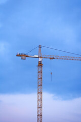 Construction cranes on the background of the sky at sunset. Construction of new residential complex.