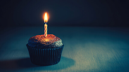 Chocolate cupcake with a lit candle in a dark moody setting