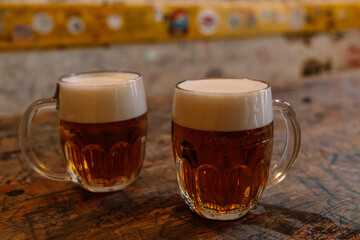 Two mugs of beer resting on wooden table in Budapest pub
