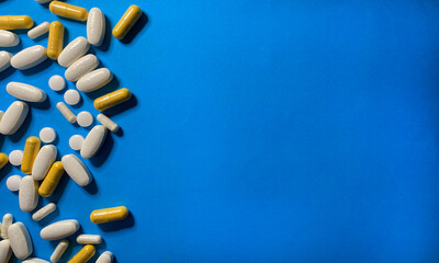 Scattered pills and vitamins on a blue background.
