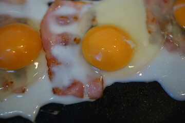 目玉焼きとベーコンをフライパンで焼く