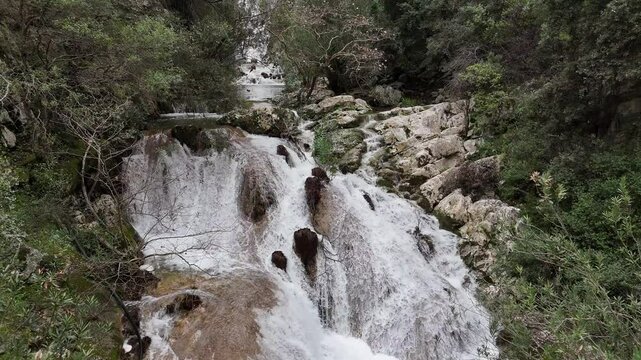 Aerial View of cascade rushes down the rocky cliffs near Polylimnio Waterfall in Messinia, Greece after heavy rainfall