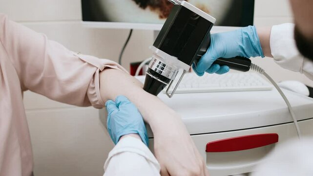 A dermatologist examines the skin of a young patient using advanced equipment, displaying cellular structure on the screen for analysis. Concept diagnosing skin diseases