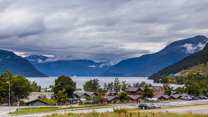 Stunning Landscape of Norwegian Fjord: Serene Waters and Majestic Mountains Under Cloudy Skies