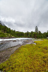 A Serene Landscape of Lush Greenery and Flowing Water Amidst Overcast Skies in a Natural Paradise Perfect for Outdoor Adventure and Exploration