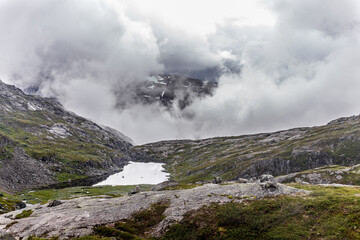 Breathtaking Mountain Landscape Surrounded by Thick Clouds and Tranquil Lake in the Norwegian Wilderness Captured with Stunning Clarity and Detail