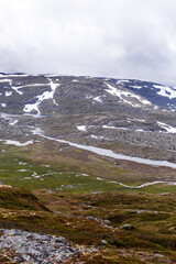 Majestic Mountain Landscape with Glacial Peaks and Flowing Waterways Under a Gloomy Sky Captures the Beauty of Nature's Unspoiled Wilderness: A Serene Countryside View
