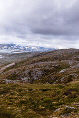Breathtaking View of Scandinavian Highlands Under Cloudy Sky with Snow-Capped Mountains and Lush Greenery in the Foreground Capturing the Beauty of Nature