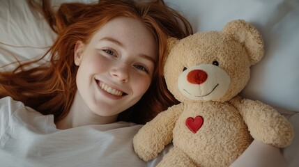 happy redhead girl lying in bed with teddy bear